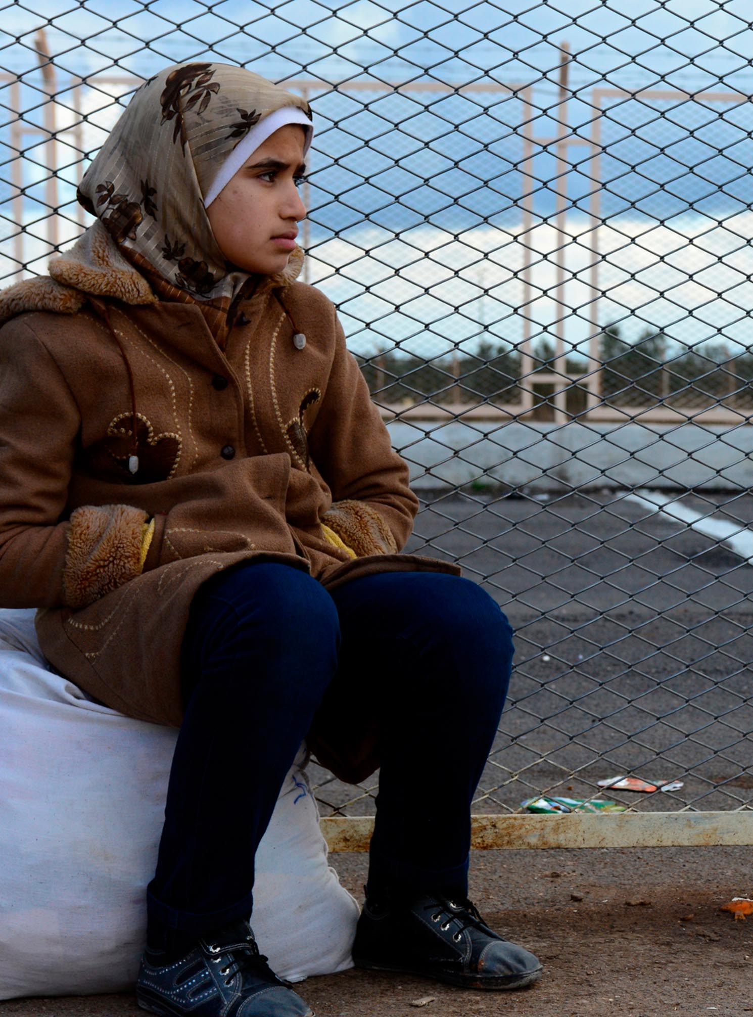 Una mujer siria espera para ser transportada a un campo de refugiados en Turqu&iacute;a.