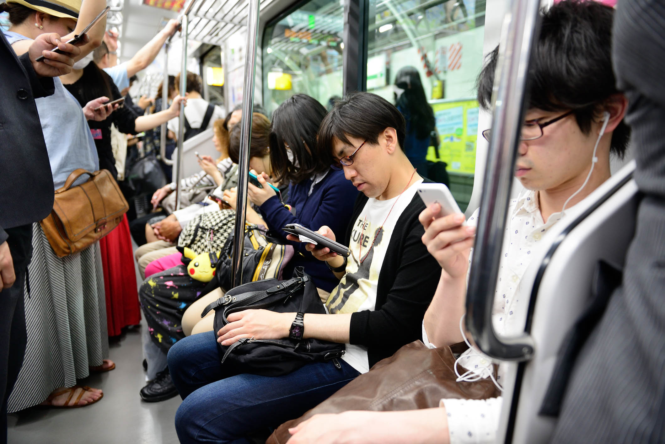 Viajeros en Tokio miran sus tel&eacute;fonos.
